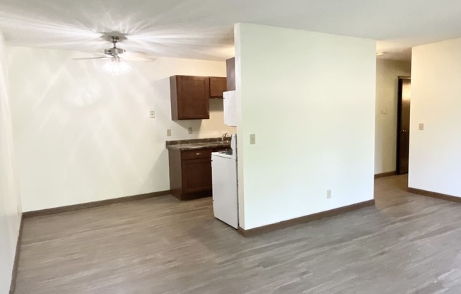 an empty living room with a white refrigerator freezer next to a stove top oven