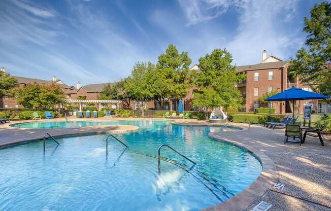 A swimming pool with a blue umbrella and a building in the background.