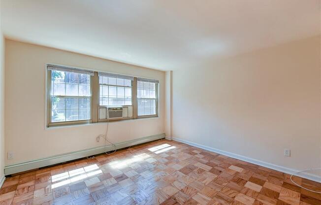 vacant living area with hardwood flooring and large windows at alpha house apartments in washington dc