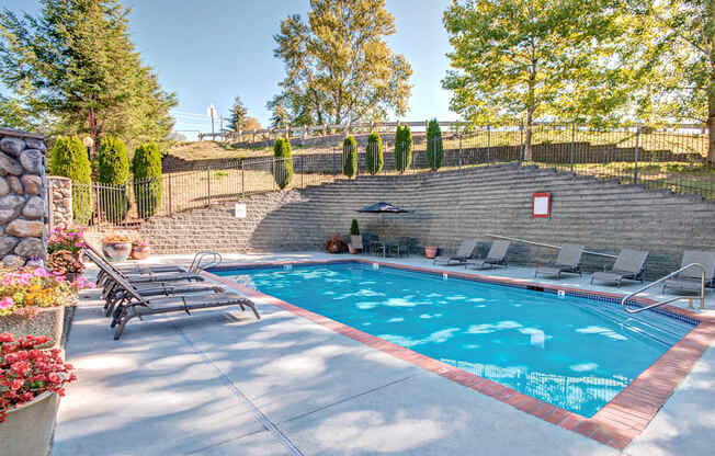 A pool surrounded by a stone wall and trees.