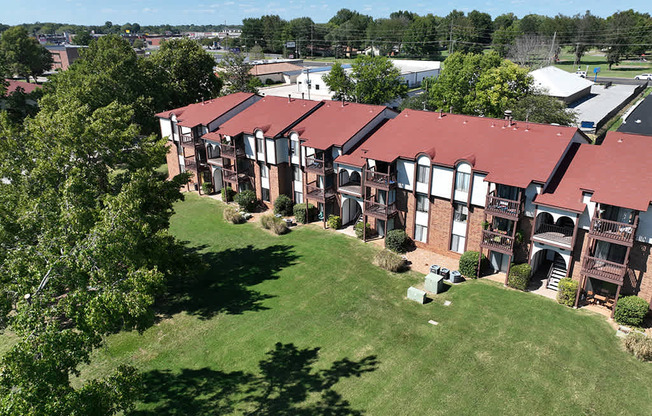 A large building with a red roof is surrounded by green grounds at Old Monterey Apartments, Springfield, MO