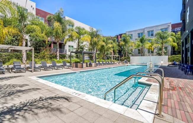 a swimming pool with chairs and a building in the background