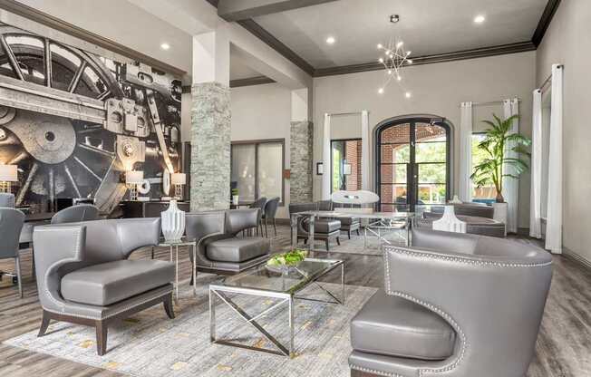 A large room with grey chairs and a table with a glass top.