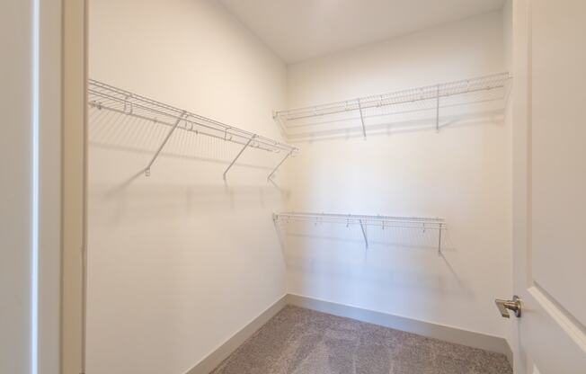 an empty closet with hanging rails and a door to a room with white walls