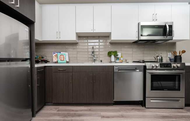 Apartments In DTLA For Rent - Kitchen With Stainless-Steel Appliances, White Cabinets, And Wood-Style Floors