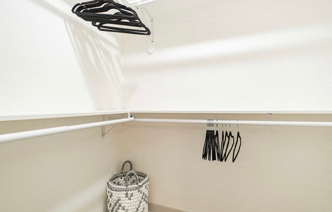 A white laundry basket sits under a clothes dryer.