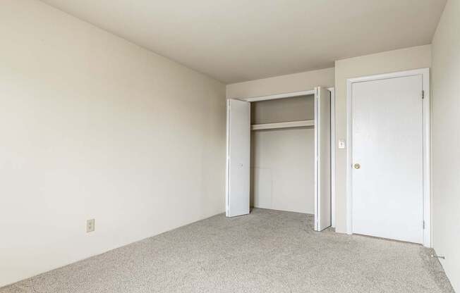 A room with a white door and a white closet with a door open.
