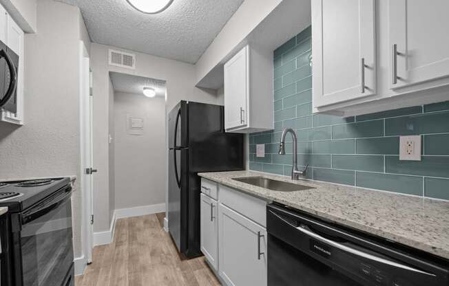 A kitchen with black appliances and white cabinets.