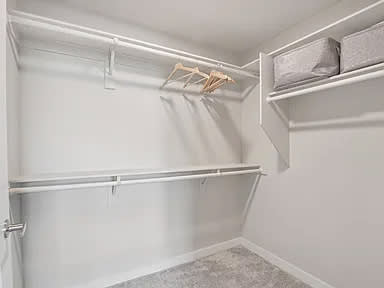 A white closet with a shelf and hangers.