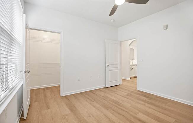 A room with a ceiling fan and wooden flooring.