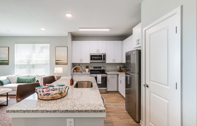 an open kitchen and living room with a granite counter top