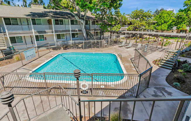 A pool surrounded by a fence and apartment buildings.