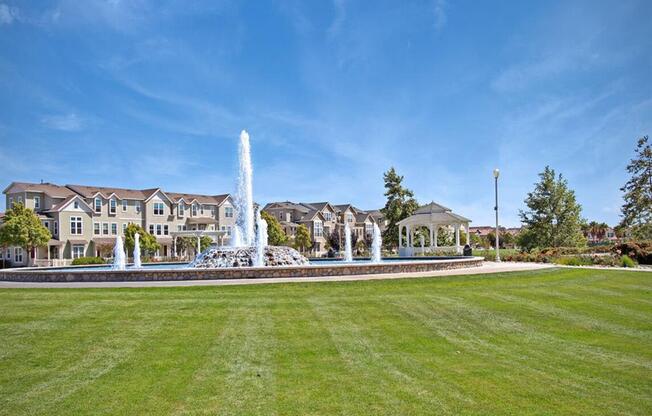 a fountain in the middle of a park with a building in the background at The Vines at Riverpark, LLC, Oxnard, 93036