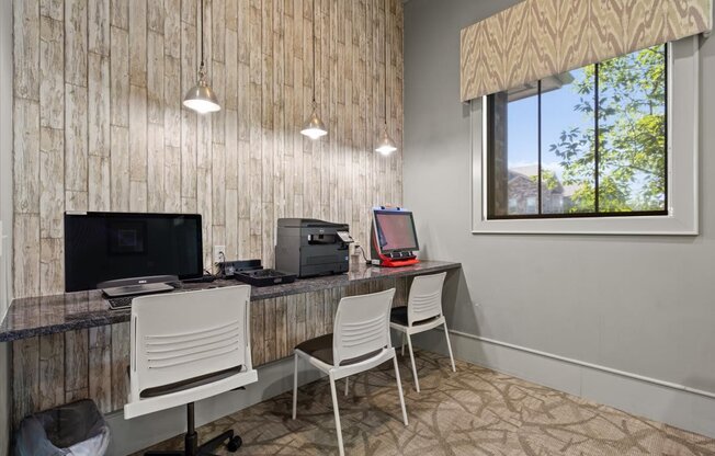 a room with two desks and two chairs with a computer monitor and printer on top of them