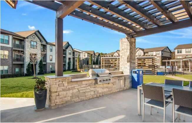 a covered patio with a grill and a table and chairs at The McKenzie Park Apartments, Little Rock, AR 72223