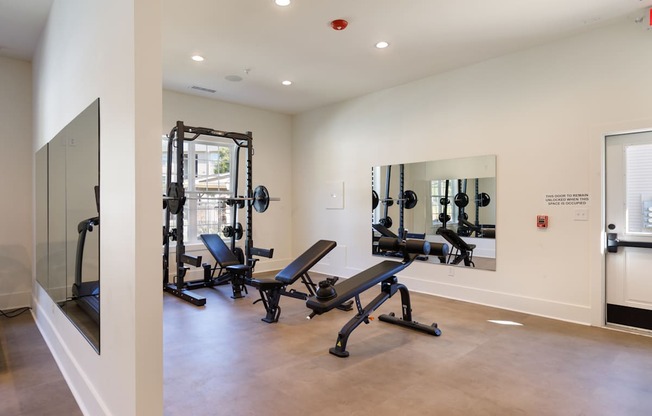 A gym with a mirror, treadmill, and weights.