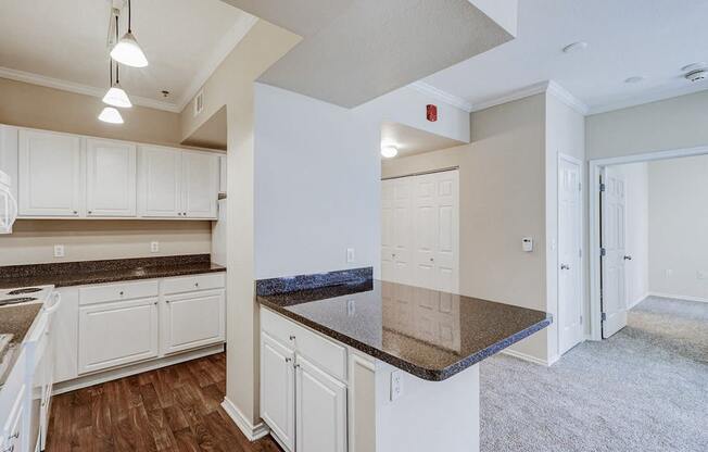 an empty kitchen with white cabinets and granite counter tops