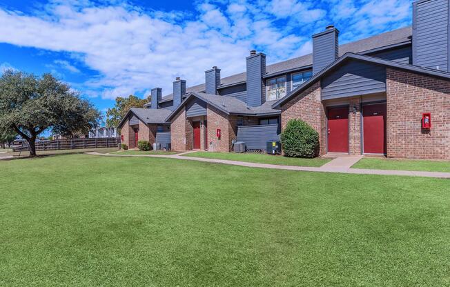 a large brick building with a grassy field