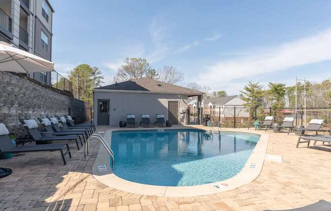a swimming pool with lounge chairs and a building in the background