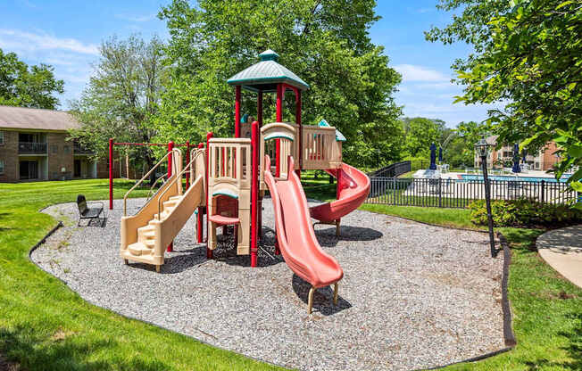 A playground with a red slide and a green roofed structure.