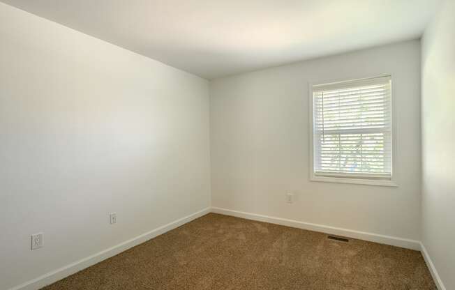 an empty room with white walls and a window