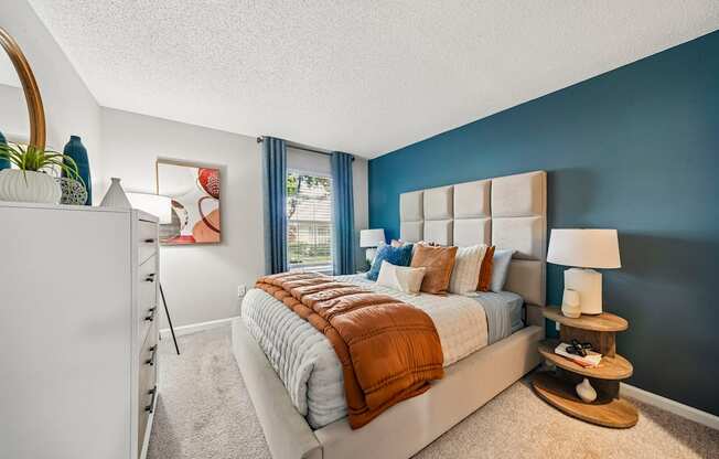 A bedroom with a large bed and a white dresser.