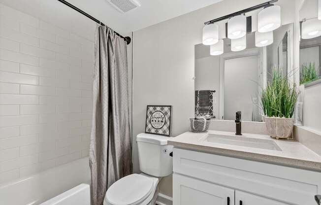 A white bathroom with a toilet, sink, and a mirror.
