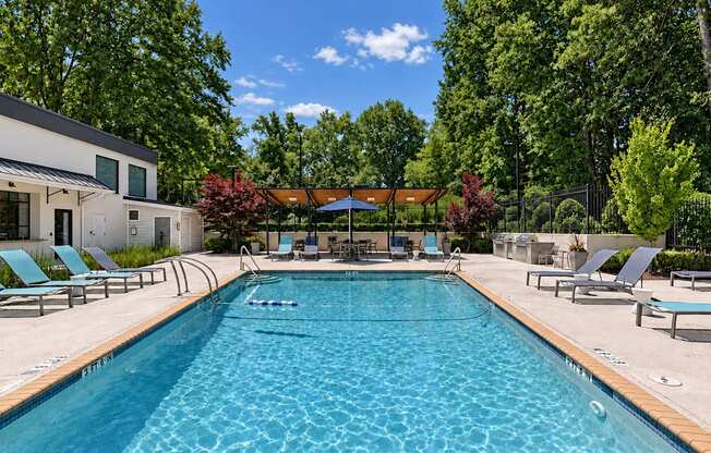 Swimming pool with lounge chairs beside the clubhouse at Icon Avondale Apartments in Decatur, GA.