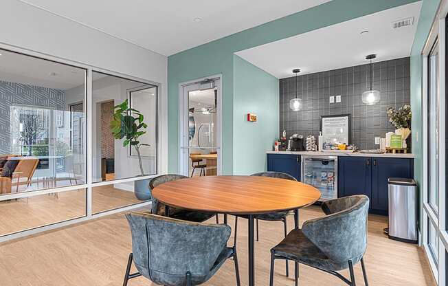 a dining area with a table and chairs and a kitchen in the background