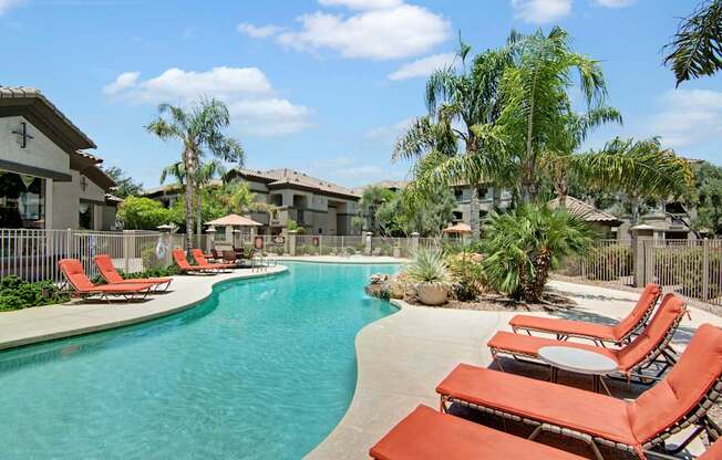 A pool surrounded by chairs and trees.