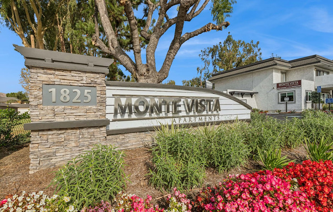 The sign for Monte Vista Apartments is surrounded by flowers and greenery.