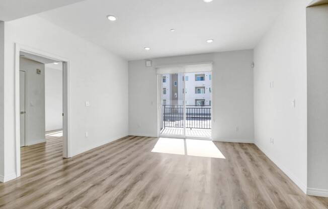 an empty living room with wood floors and a balcony