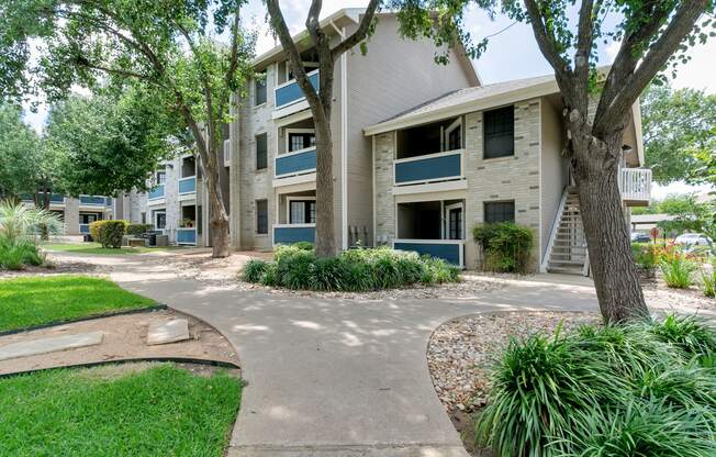 an apartment building with a walkway and trees in front of it