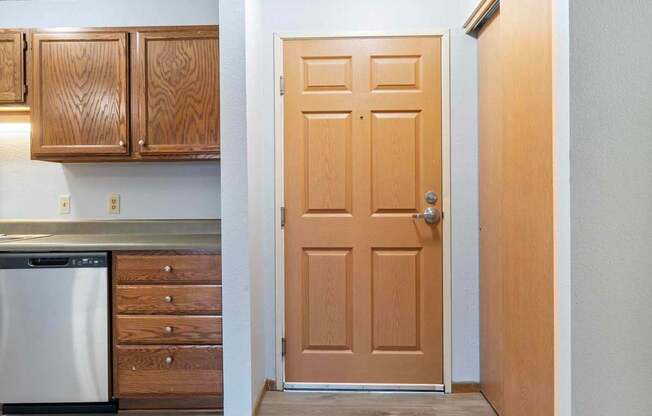 A kitchen with a wooden door and a dishwasher.