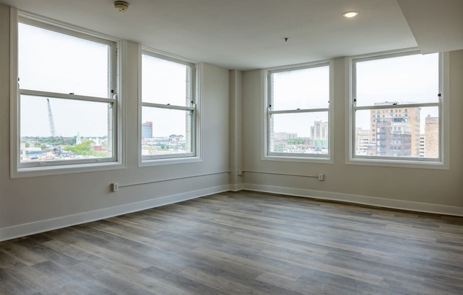 an empty living room with wood floors and four windows