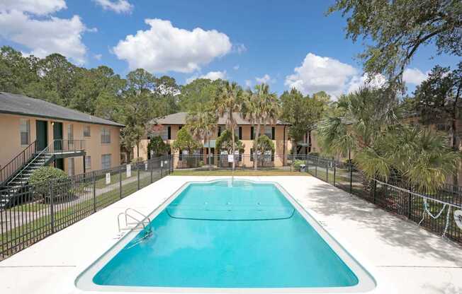 A swimming pool surrounded by a fence and trees.