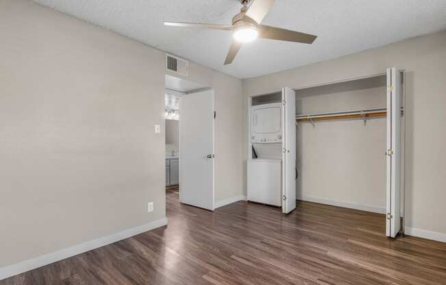 the spacious living room with a ceiling fan and a laundry room