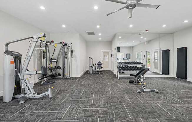 A spacious fitness center with a variety of equipment including treadmills and strength training machines at Jefferson Place Apartments in Irving, TX