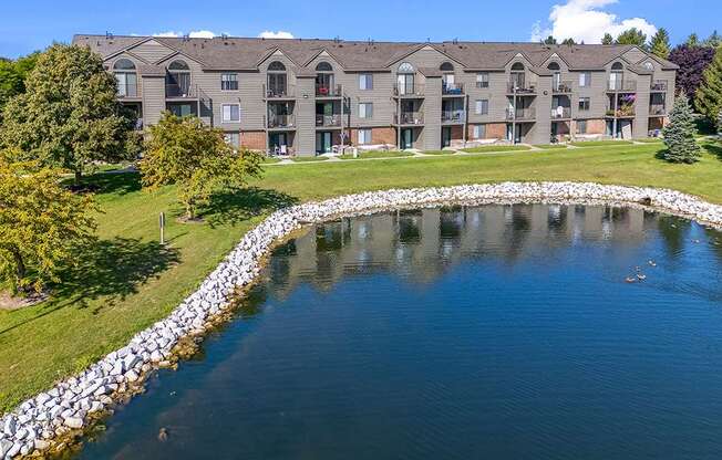 The rear view of a building with a pond in back at Oak Shores Apartments in Oak Creek, WI