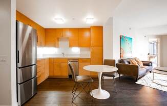 A kitchen with orange cabinets and a white table.