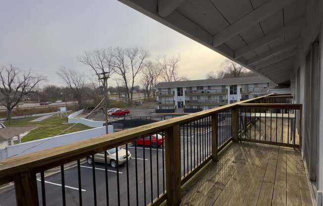 a balcony with a wooden railing overlooking a parking lot