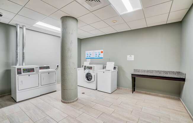 a laundry room with washer and dryers and a table at Cherry Street Lofts in Bridgeport, CT, 06605