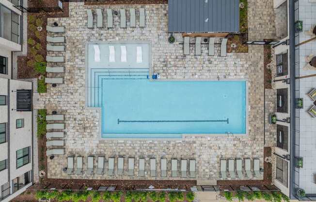 A swimming pool surrounded by a stone wall and lounge chairs.