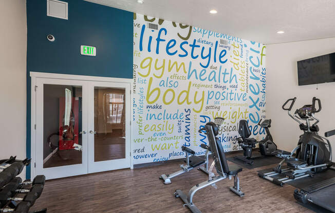 a gym with exercise machines and a wall with words on it