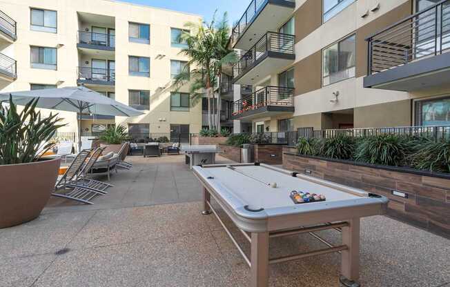 A pool table is in the middle of a courtyard surrounded by buildings.