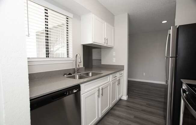 a kitchen with white cabinets and a sink and a window