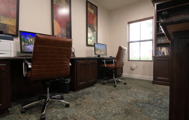 A room with two chairs and two computers.