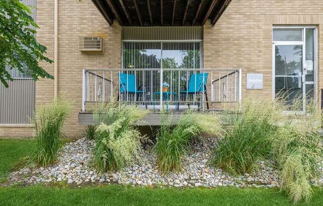 two blue chairs on a balcony in front of a brick building