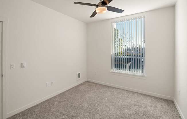 Bedroom with carpet and ceiling fan. Large window. at POLARIS AT SEATAC, SEATAC, WA
