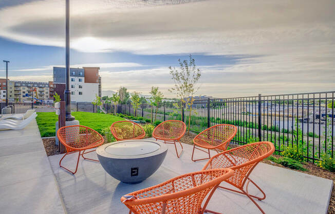 a patio with a fire pit and wicker furniture on a sunny day at Copper 87, West Jordan Utah